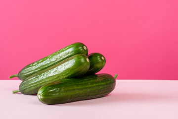 Ripe cucumbers on pink background front view copy space still life