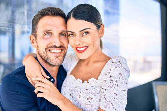 Young beautiful couple smiling happy and confident. Sitting with smile on face hugging at restaurant.