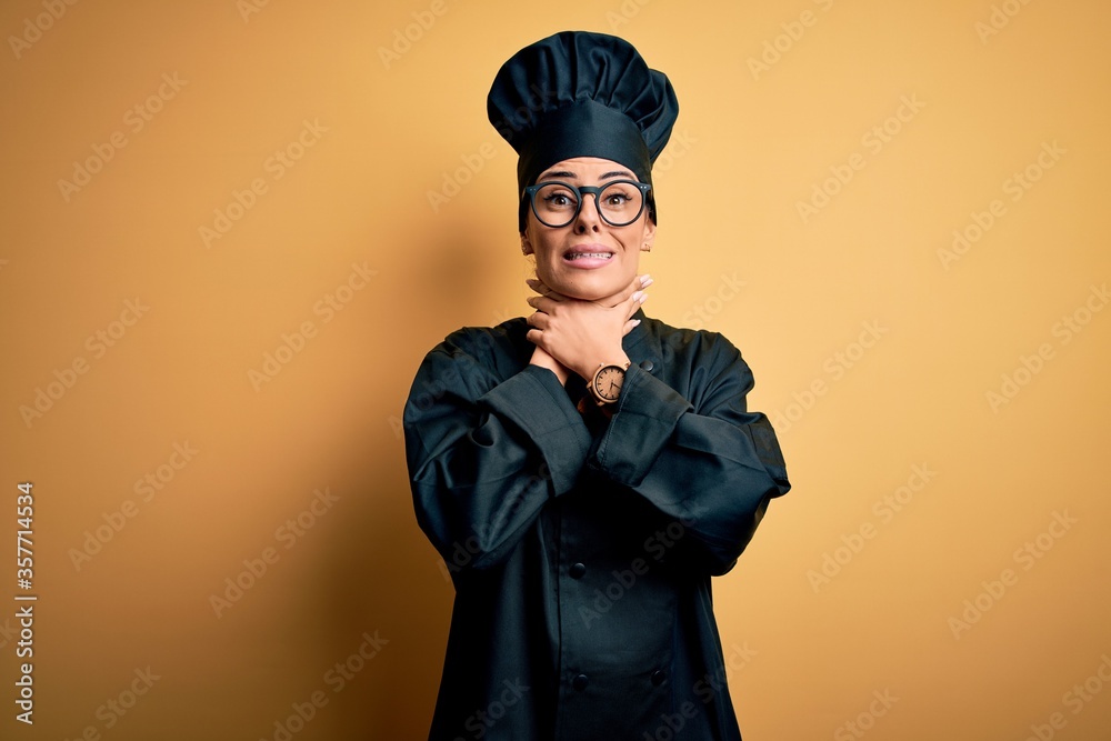 Poster Young beautiful brunette chef woman wearing cooker uniform and hat over yellow background shouting and suffocate because painful strangle. Health problem. Asphyxiate and suicide concept.