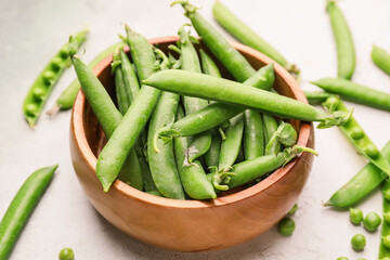 Bowl with tasty fresh peas on light background