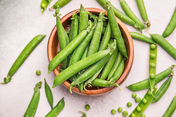 Bowl with tasty fresh peas on light background