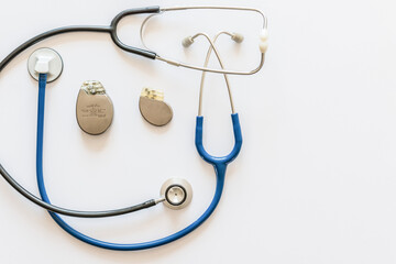 two blue and black stethoscopes on a white background with pacemaker battery