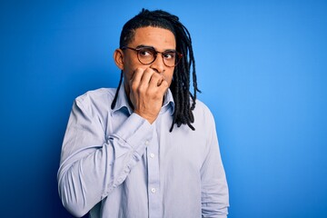 Young handsome african american man with dreadlocks wearing casual shirt and glasses looking stressed and nervous with hands on mouth biting nails. Anxiety problem.