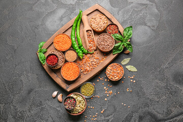 Different raw legumes with spices on dark background