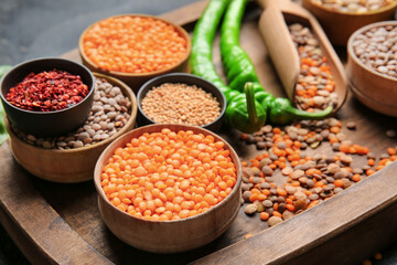 Different raw lentils with spices on board