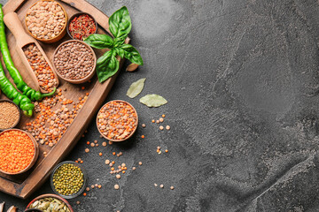 Different raw legumes with spices on dark background
