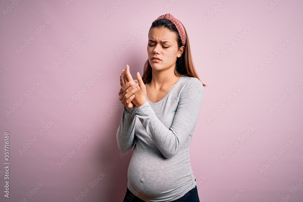 Wall mural Young beautiful teenager girl pregnant expecting baby over isolated pink background Suffering pain on hands and fingers, arthritis inflammation - Wall murals
