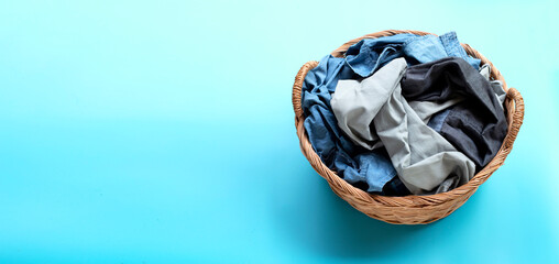 Clothes in laundry basket on blue background.