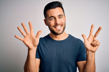 Naklejka premium Young handsome man wearing casual t-shirt standing over isolated white background showing and pointing up with fingers number eight while smiling confident and happy.