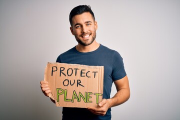 Young handsome activist man protesting for the enviroment hoding cardboard with a happy face standing and smiling with a confident smile showing teeth