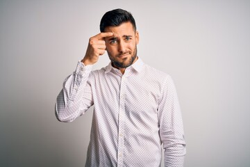 Young handsome man wearing elegant shirt standing over isolated white background pointing unhappy...