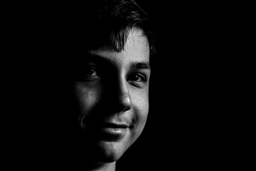 Portrait of a teenager on a black background. The boy has dark hair
