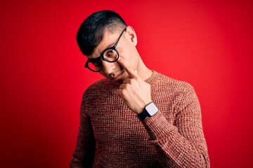 Young handsome hispanic man wearing nerd glasses over red background Pointing to the eye watching...
