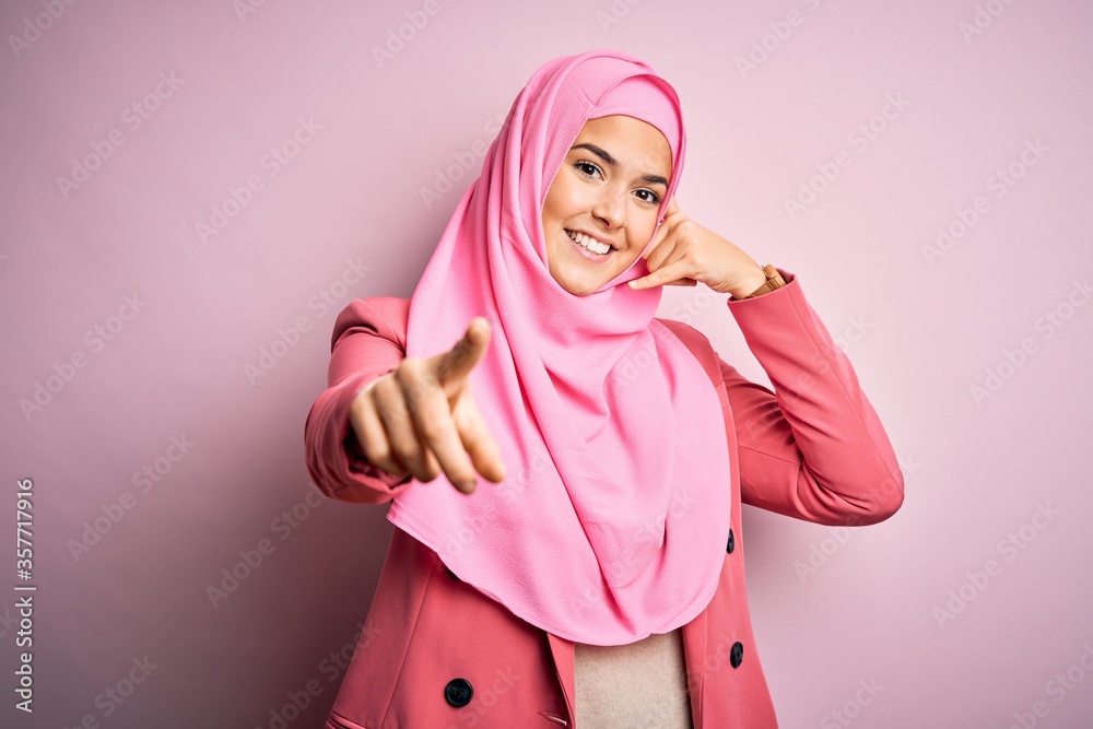 Poster young beautiful girl wearing muslim hijab standing over isolated pink background smiling doing talki