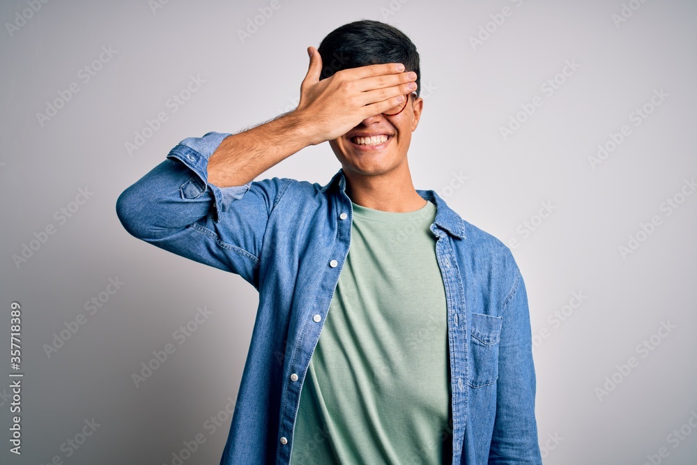 Canvas Prints Young handsome man wearing casual shirt and glasses over isolated white background smiling and laughing with hand on face covering eyes for surprise. Blind concept.