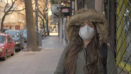 Pandemic, portrait of a young beautiful woman wearing protective mask on street without people during lockdown quarantine due Coronavirus COVID 19 outbreak. Concept of danger, loneless, health, aware