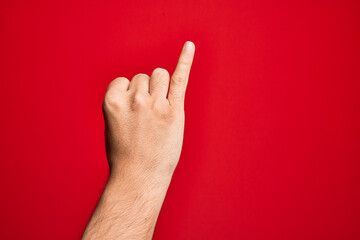 Hand of caucasian young man showing fingers over isolated red background showing little finger as...