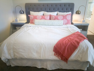 Double bed with gray upholstered headboard and white and pink beddings