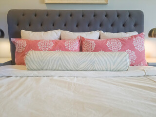 Double bed with fluffy pillows against gray upholstered headboard