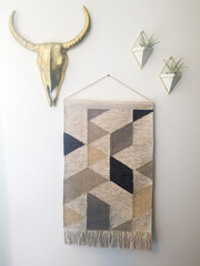 Woven tapestry metal bull head and plant hanger decorations against white wall
