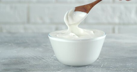 Man's hand with a spoon mixing the sour cream in a bowl.