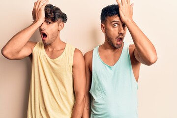 Young gay couple wearing casual clothes surprised with hand on head for mistake, remember error....