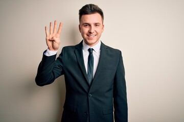 Young handsome business man wearing elegant suit and tie over isolated background showing and pointing up with fingers number four while smiling confident and happy.