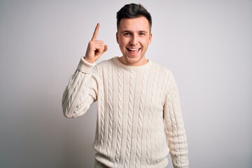 Young handsome caucasian man wearing casual winter sweater over white isolated background pointing finger up with successful idea. Exited and happy. Number one.