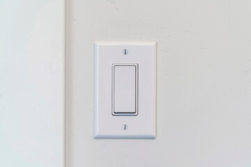 Electrical rocker light switch with flat broad lever on white interior wall