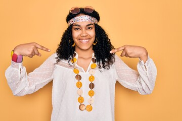 Young african american curly hippie woman wearing sunglasses and vintage accessories looking...