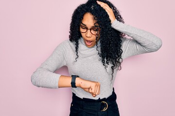 Young african american woman wearing turtleneck sweater and glasses over pink background Looking at...