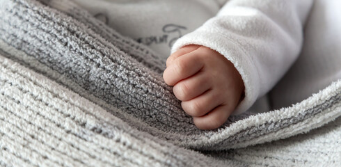 Fototapeta na wymiar Baby's baby hand close-up. The child sleeps and put his hand on the gray plaid.