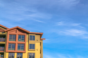 Fototapeta na wymiar Home exterior with balconies and multi color walls against blue sky and clouds