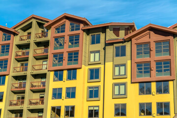 Residential building with multi color wall and small balconies against blue sky
