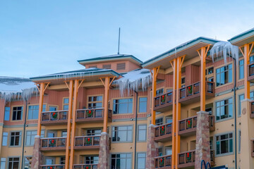 Fototapeta premium Residential building with fresh snow and sharp icicles on the roof in winter