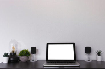 Laptop on a black desk/table with speakers, lamp and succulent plants against a white wall. Productive workspace to study, listen to music, and work. Room for text at the top. Scandinavian style.