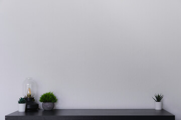 A simple black desk with succulents and an Edison lamp against a white wall. A clean and modern...
