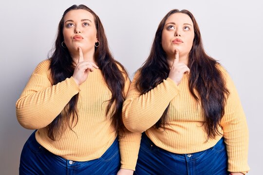 Young plus size twins wearing casual clothes thinking concentrated about doubt with finger on chin and looking up wondering