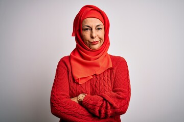 Middle age brunette woman wearing muslim traditional hijab over isolated white background skeptic...