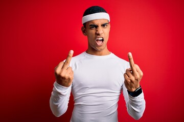 Young handsome african american sportsman wearing sportswear over red background Showing middle...