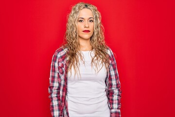 Young beautiful blonde woman wearing casual shirt standing over isolated red background looking sleepy and tired, exhausted for fatigue and hangover, lazy eyes in the morning.