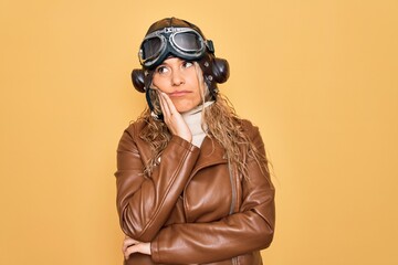 Young beautiful blonde aviator woman wearing vintage pilot helmet whit glasses and jacket thinking looking tired and bored with depression problems with crossed arms.