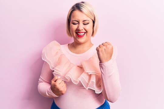 Young beautiful blonde plus size woman wearing casual sweater over isolated pink background celebrating surprised and amazed for success with arms raised and eyes closed