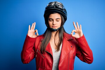Young beautiful brunette motorcycliste woman wearing motorcycle helmet and jacket relax and smiling with eyes closed doing meditation gesture with fingers. Yoga concept.