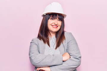 Young plus size woman wearing architect hardhat happy face smiling with crossed arms looking at the camera. positive person.