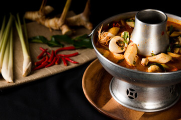 A delicious seafood soup of Thai people in a hot pot on a black background. Seafood Tom Yum with Coconut Milk