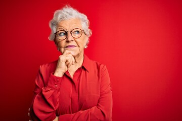 Senior beautiful grey-haired woman wearing casual shirt and glasses over red background with hand...