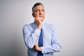 Middle age handsome grey-haired business man wearing elegant shirt and tie with hand on chin thinking about question, pensive expression. Smiling and thoughtful face. Doubt concept.