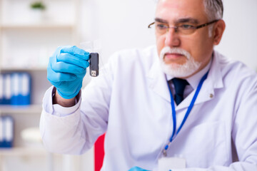 Old male expert criminologist working in the lab for evidence