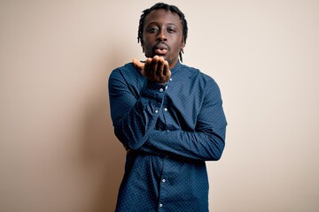 Young handsome african american man wearing casual shirt standing over white background looking at the camera blowing a kiss with hand on air being lovely and sexy. Love expression.